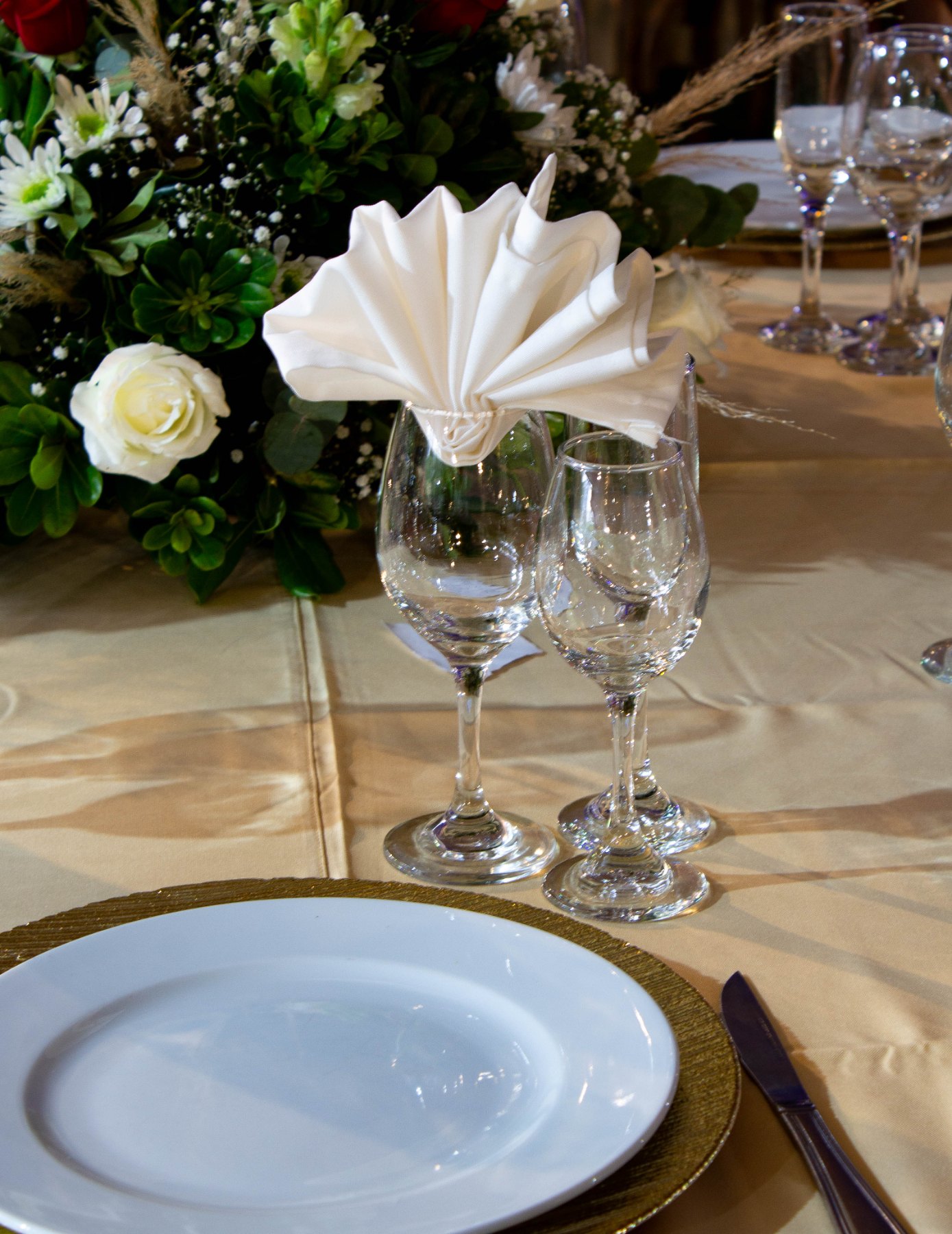 Copas y centro floral sobre mantel dorado
