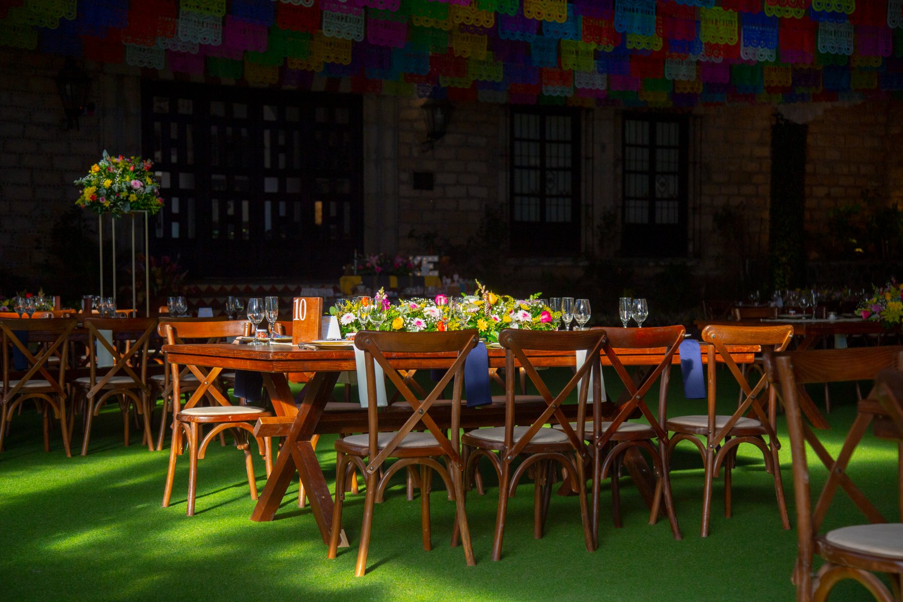 Mesas largas con sillas cross-back y papel picado
