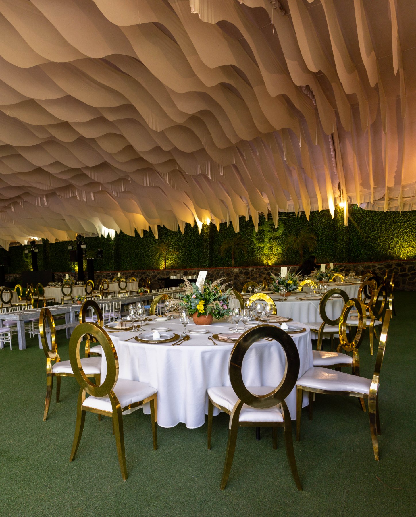 Carpa con sillas doradas y mesas redondas